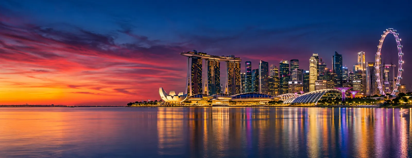 Singapore city skyline of office and residential towers at blue hour, lights reflected in the water